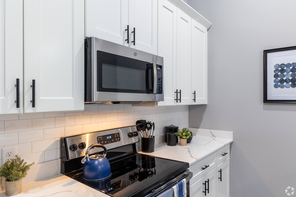A modern kitchen with a black stove top and white cabinets.
