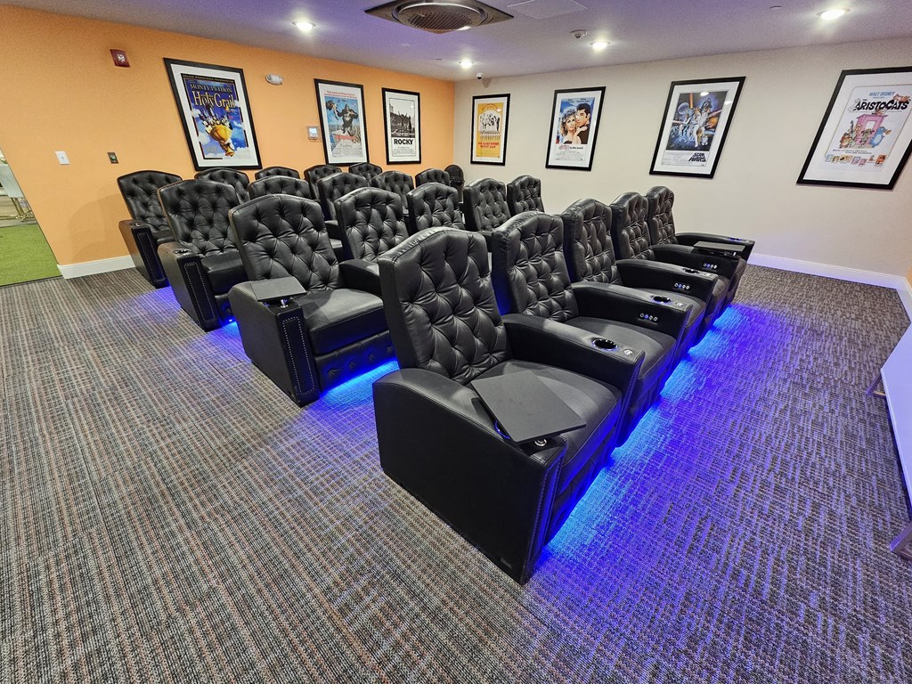 a theater room with a row of black chairs and blue lights