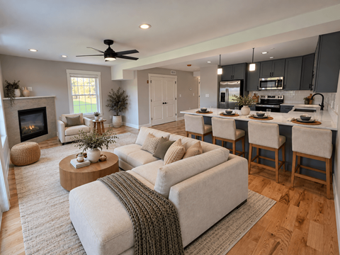 A modern living room with a fireplace and a kitchen area in the background.