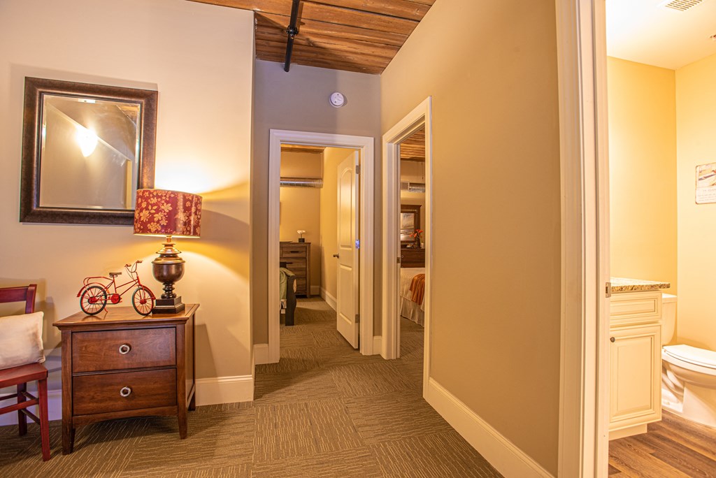 a living room with a dresser and a mirror and a bathroom with a toilet