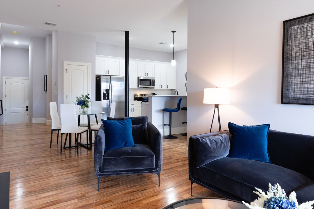 A modern living room with a black couch and a dining table.