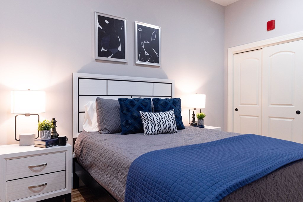 A bedroom with a bed, nightstand, and two framed pictures on the wall.