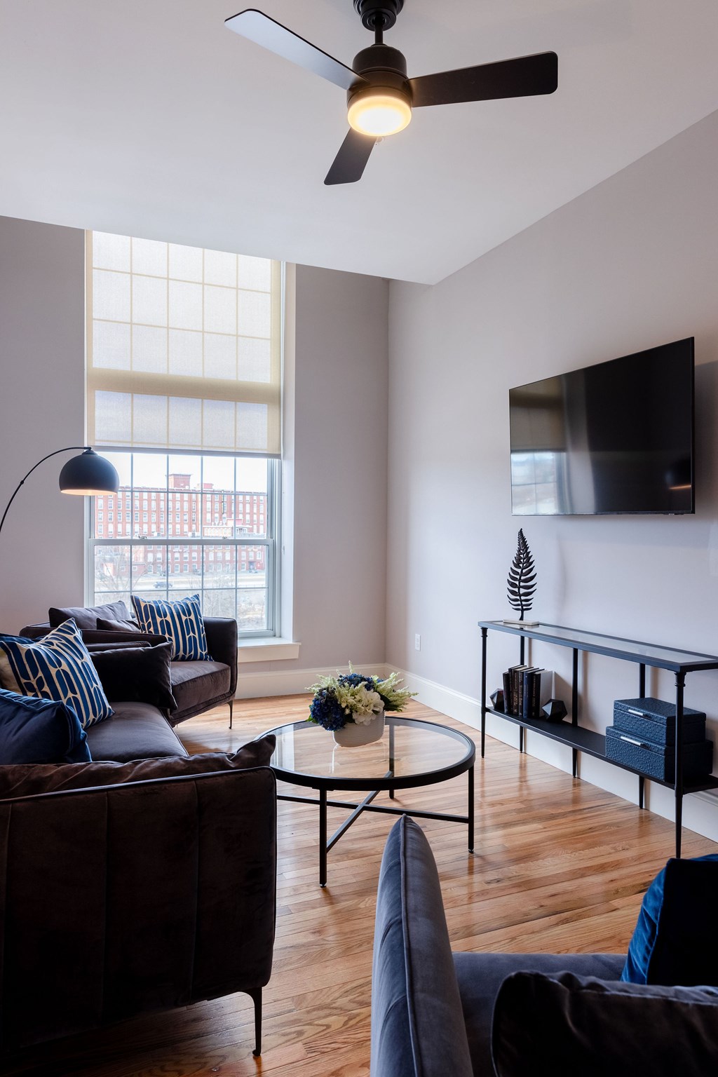 A living room with a dark brown couch, a black coffee table, and a ceiling fan.