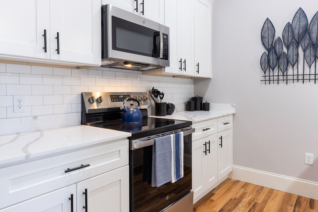 A kitchen with white cabinets and a black countertop.