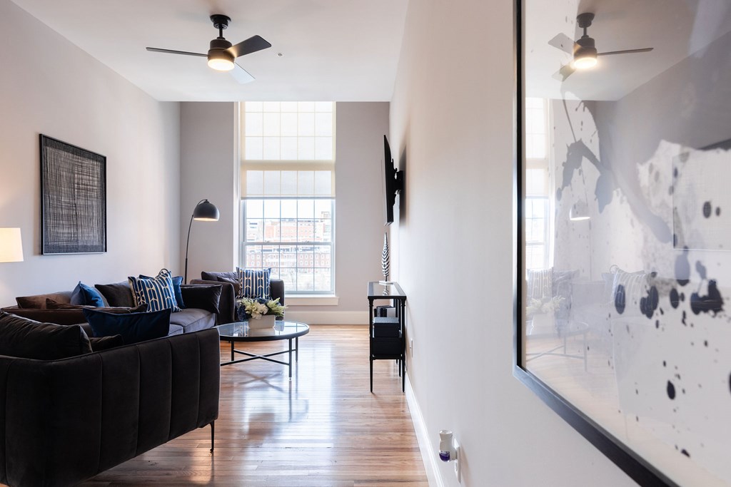 A living room with a black couch and a large abstract painting on the wall.