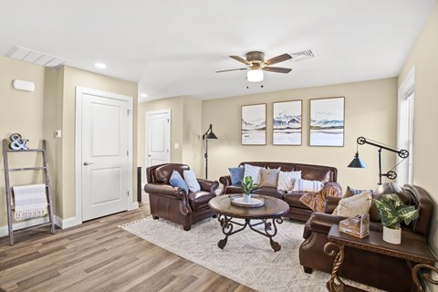 a living room with leather furniture and a ceiling fan