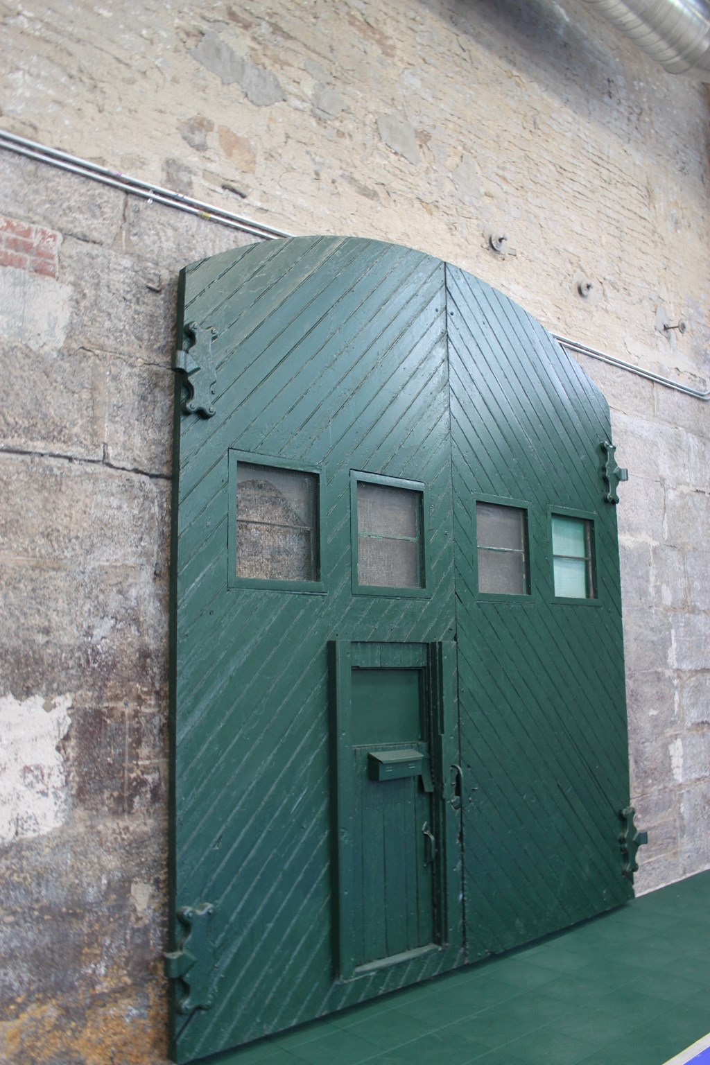 a green door to a jail cell with three windows