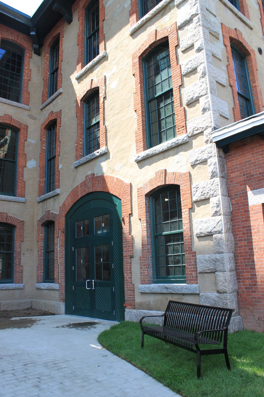 a bench in front of a brick building with a green door