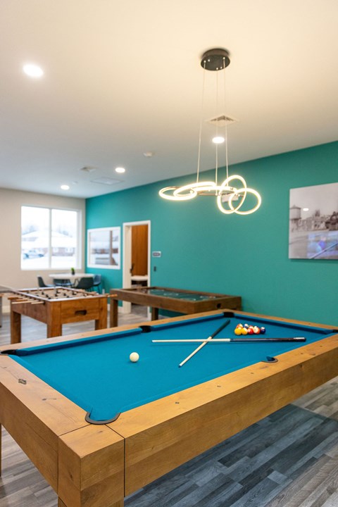 A pool table with a green cloth and a white cue ball and red balls on it.