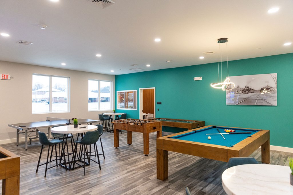 A room with a pool table and a picture of a house on the wall.