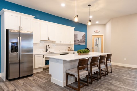 A kitchen with a white island and wooden chairs.