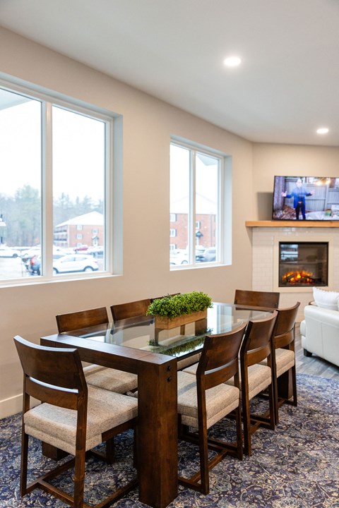 A dining room with a table and chairs and a tv on the wall.