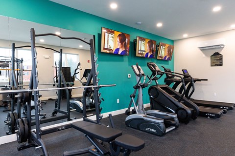 A gym with a variety of equipment including treadmills, weights, and exercise machines.