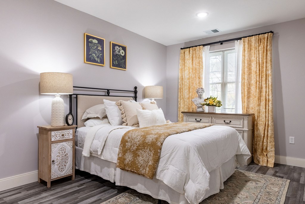 A bedroom with a large bed and a nightstand with a lamp.