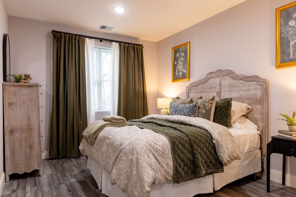 A bedroom with a large bed and a window with curtains.
