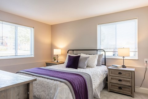 A bedroom with a bed, nightstand, and window.