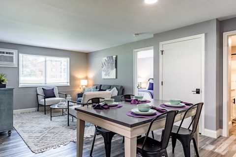 A dining room with a table set for two and chairs around it.
