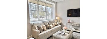 A living room with a couch, a coffee table, and a flat screen TV mounted on the wall.