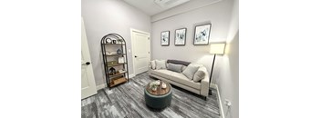 A living room with a grey couch, a wooden coffee table, and a black bookshelf.
