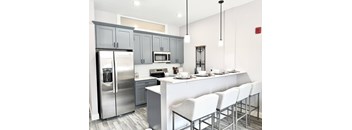 A modern kitchen with a white island and grey cabinets.