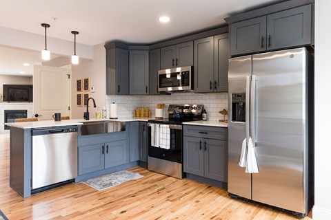 A modern kitchen with dark grey cabinets and stainless steel appliances.