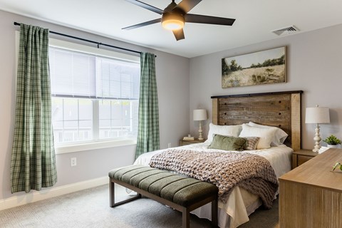 A bedroom with a bed, a bench, and a painting on the wall.