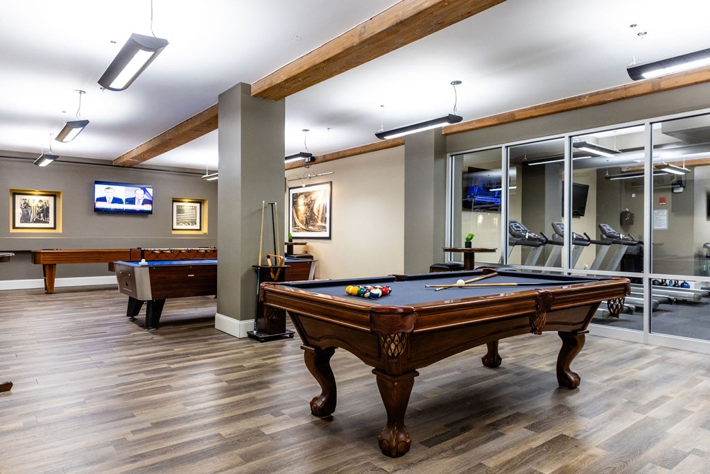 A pool table is in the middle of a room with a wooden floor.