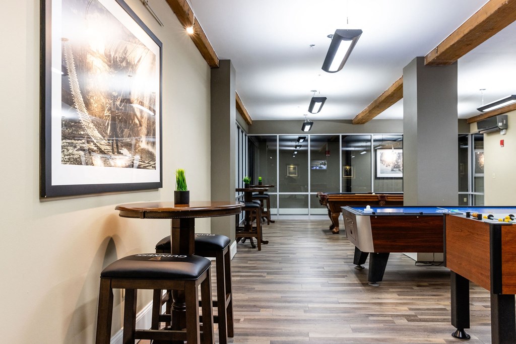 A pool table is in a room with a bar and stools.
