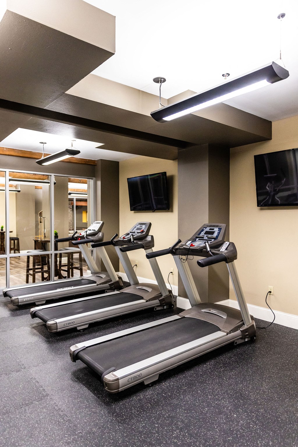 Three treadmills are lined up in a row in a gym.