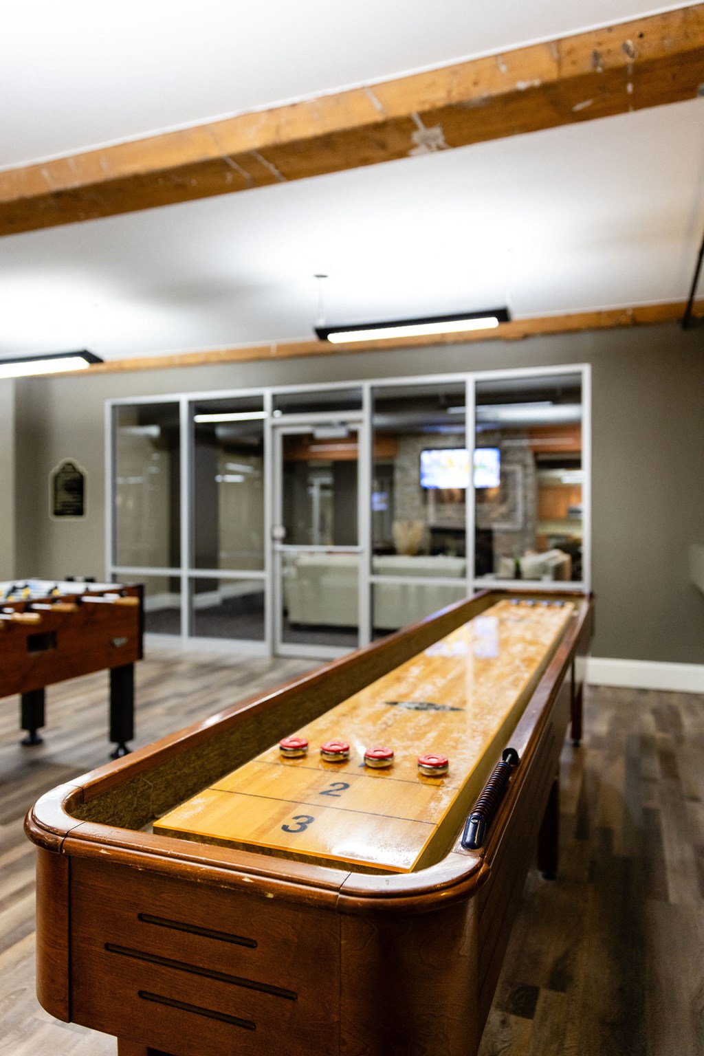 A shiny wooden pool table with green felt and red balls.