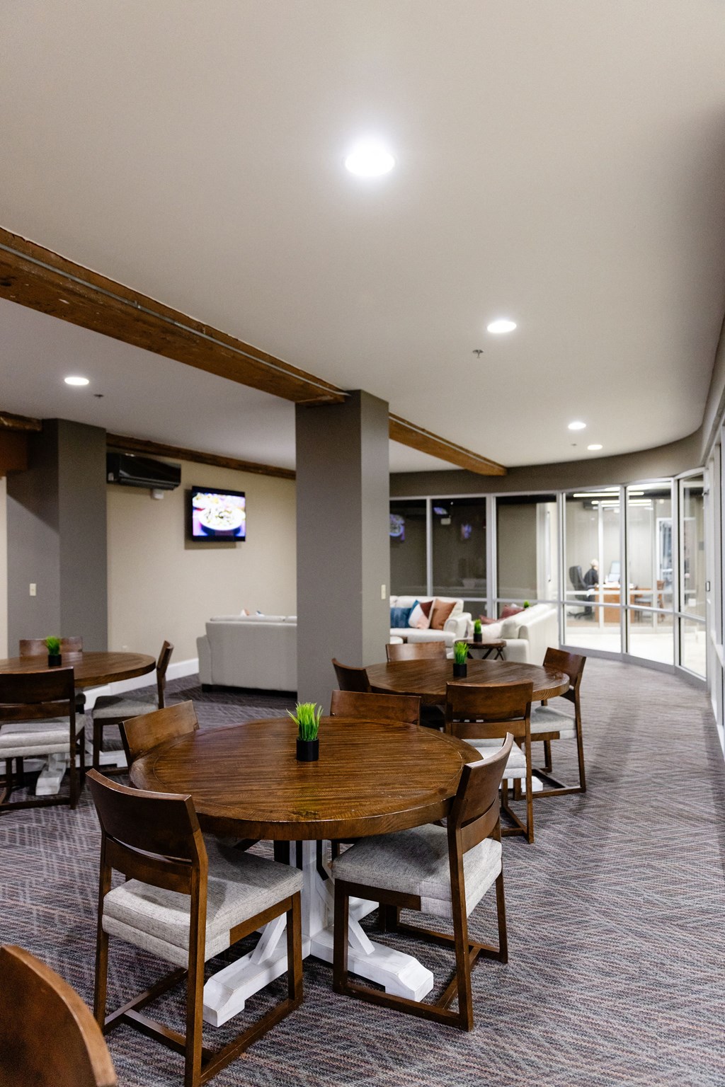 A conference room with a TV on the wall and a table with chairs.