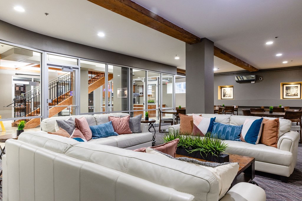 A modern living room with a white sofa and a staircase in the background.