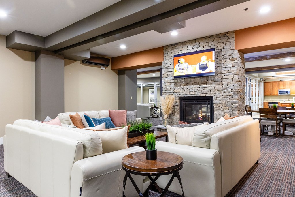 A living room with a stone fireplace and a flat screen TV mounted above it.