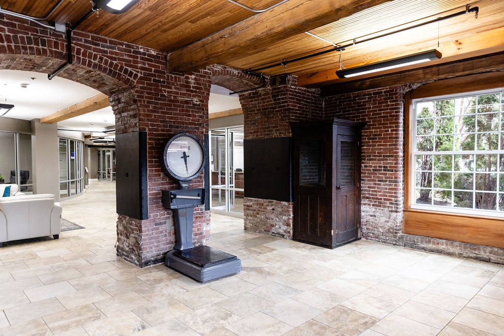 A brick column with a clock on it stands in a room with a wooden ceiling.