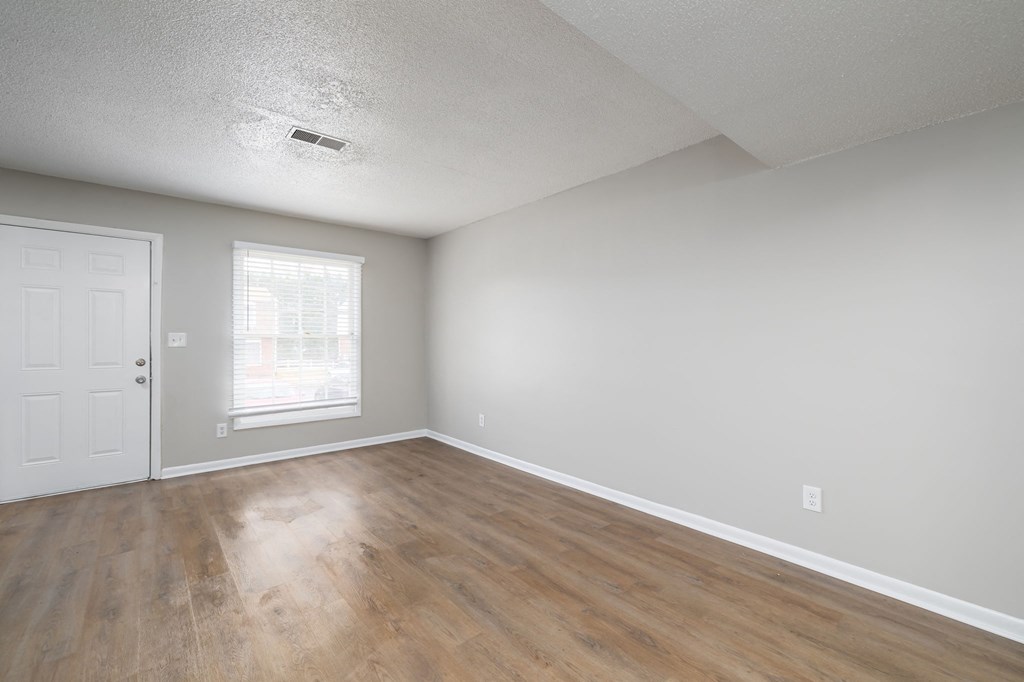 an empty living room with white walls and wood floors