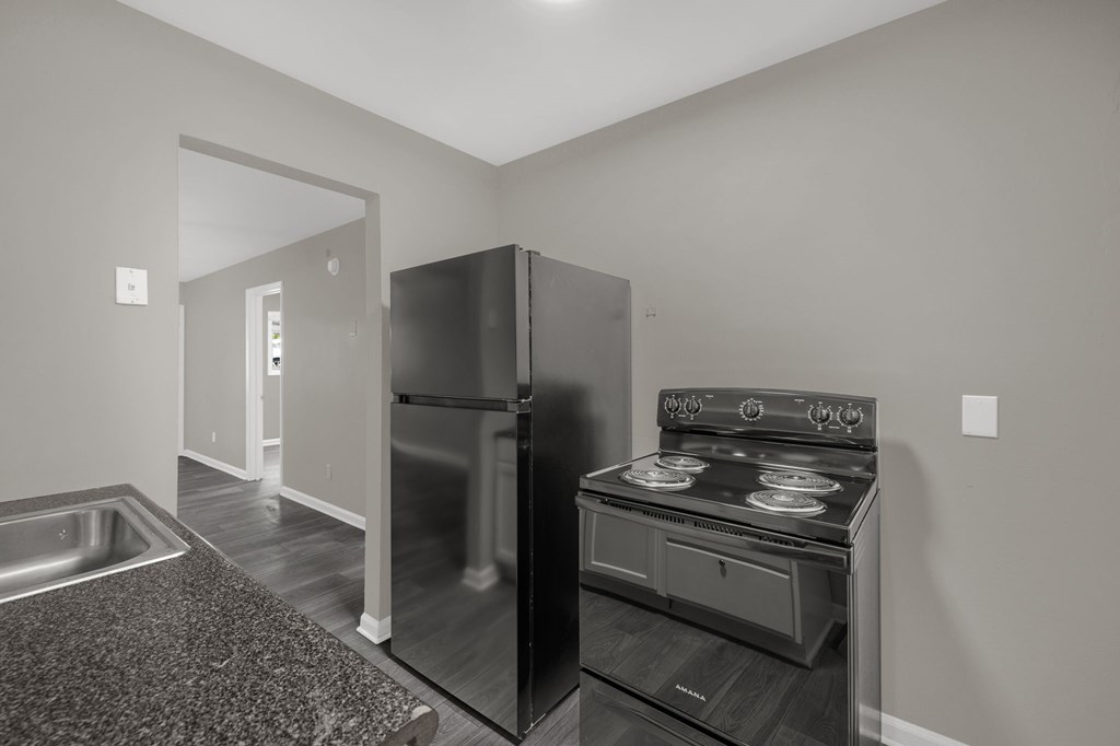 A black stove is in a kitchen with a refrigerator and a sink.
