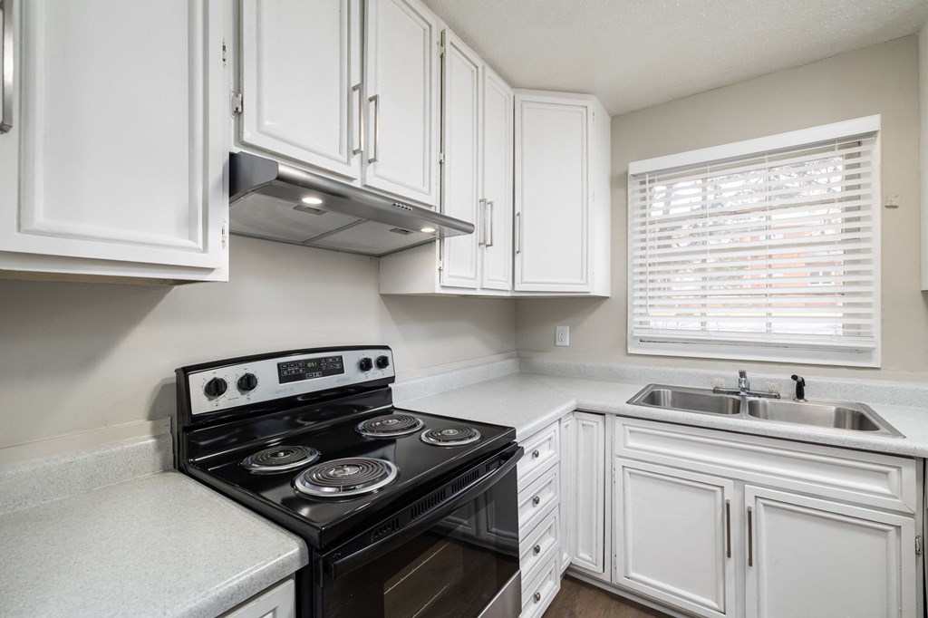 a kitchen with white cabinets and a black stove