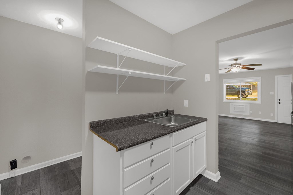 A kitchen with white cabinets and a dark countertop.