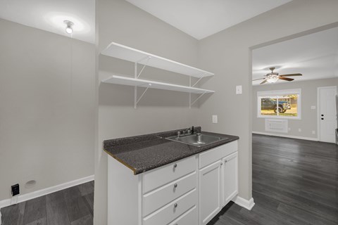 A kitchen with white cabinets and a dark countertop.