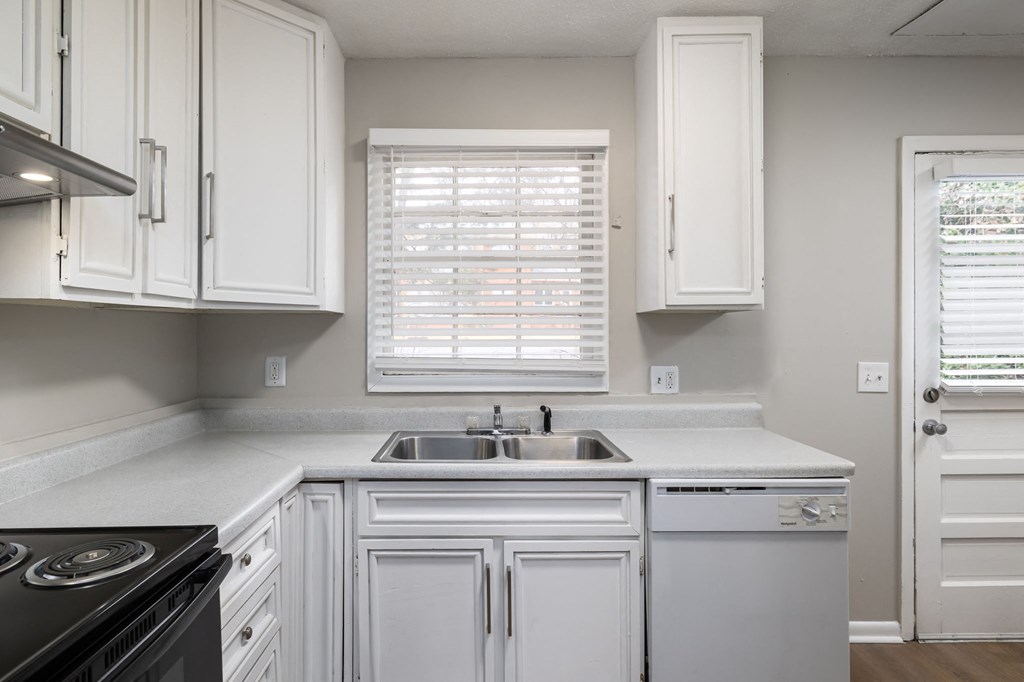 a kitchen with white cabinets and a sink and a window