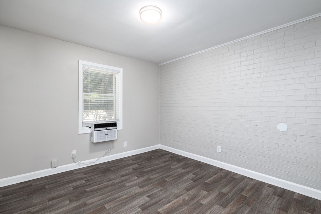 an empty living room with wood flooring and a window