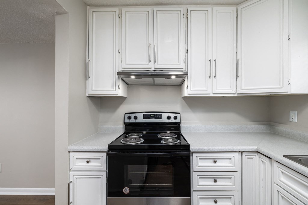 a kitchen with white cabinets and a black stove