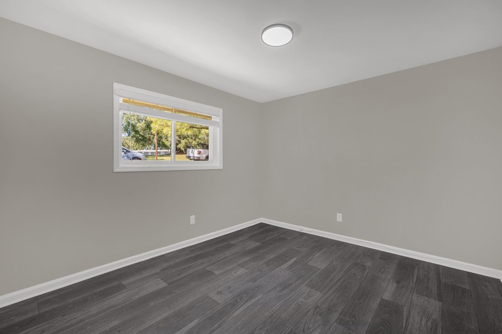 A room with a grey floor and a picture frame on the wall.