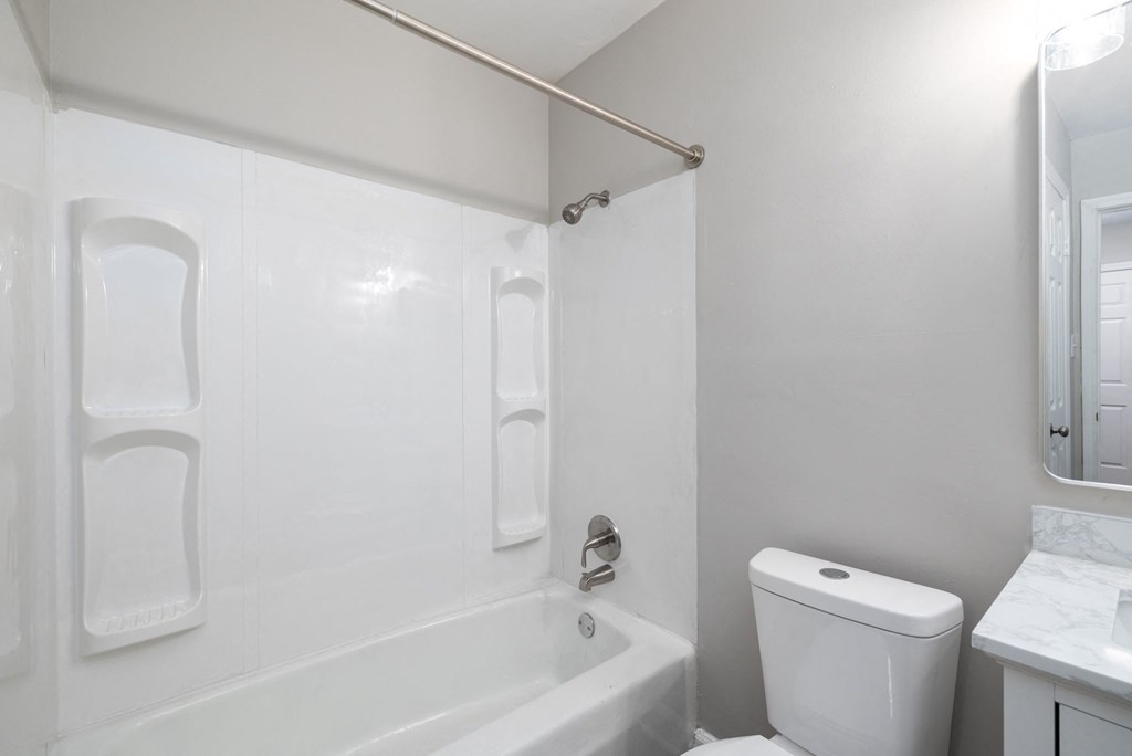 a white bathroom with a tub and a toilet and a sink