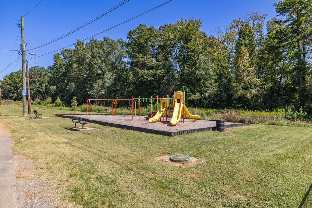 A playground with a yellow slide and a bench.