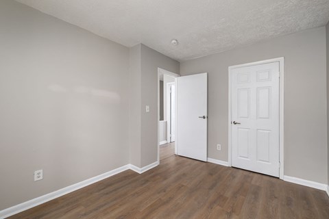 an empty living room with a white door and wood floors