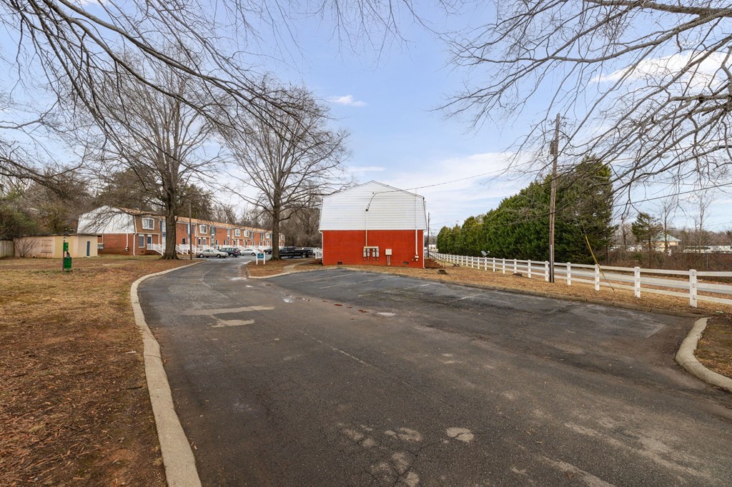 a road leading to a red and white barn on a farm