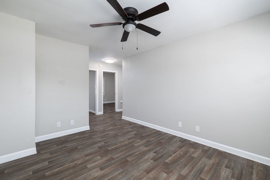 a living room with white walls and a ceiling fan