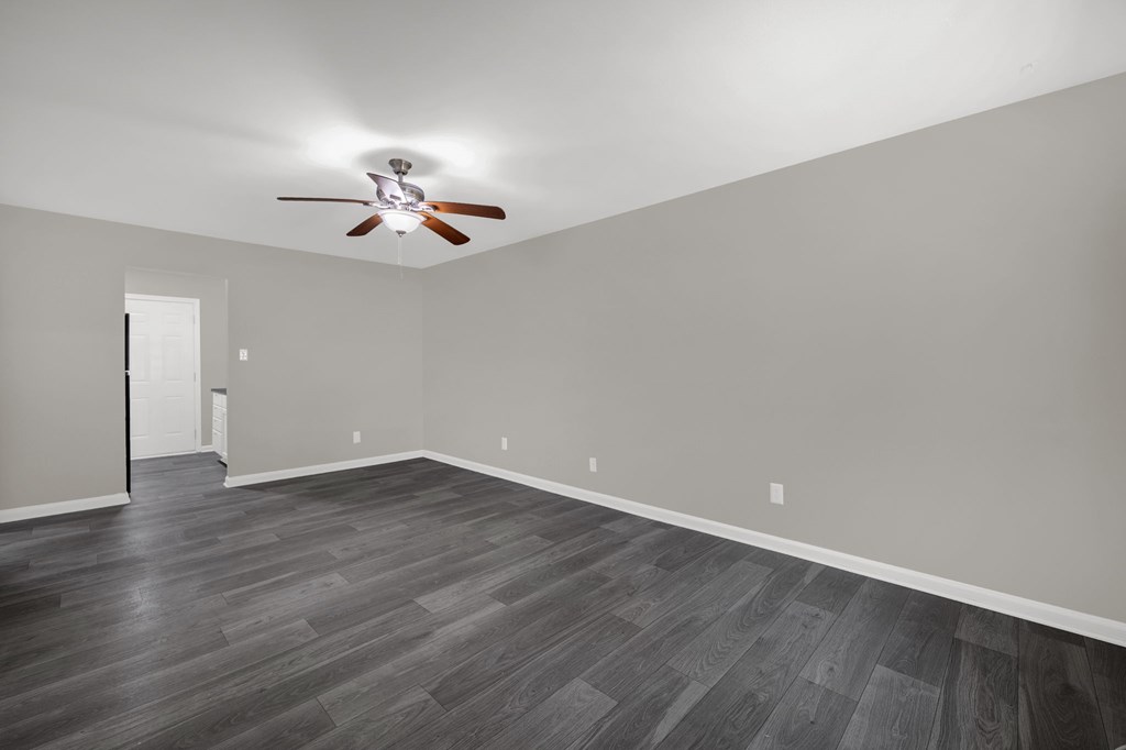A room with a ceiling fan and wooden flooring.