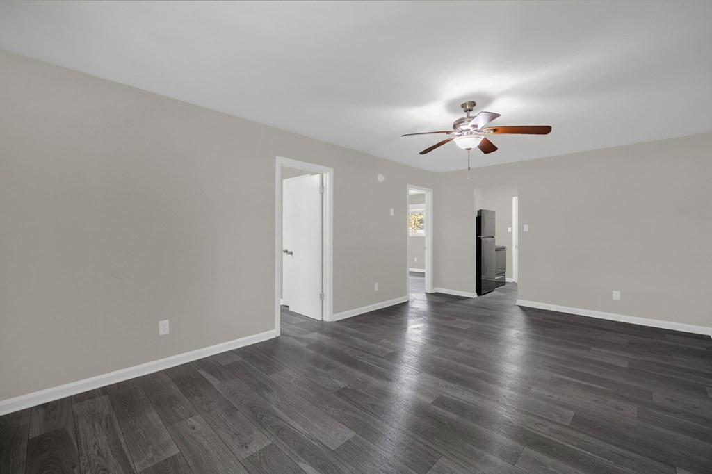 A room with a ceiling fan and wooden flooring.